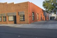 a red building with white trim and windows is on the side of a street with black shutters