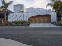 the modern home has a curved design on its facade and features a garage with lots of potted plants