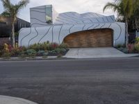 the modern home has a curved design on its facade and features a garage with lots of potted plants