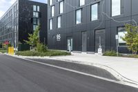 a person riding a motorcycle down a road between two buildings in front of some trees