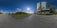 a wide angle view of a road outside a building with several trees and grass around it