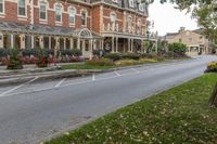 a large red brick building sits next to a tree near the street and lawn of some homes