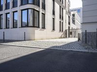 a building is on the side of the street with cobblestone walkway on one side