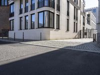 a building is on the side of the street with cobblestone walkway on one side