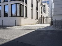 a building is on the side of the street with cobblestone walkway on one side