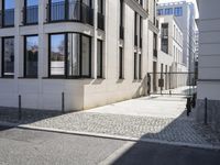 a building is on the side of the street with cobblestone walkway on one side