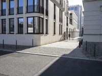 a building is on the side of the street with cobblestone walkway on one side