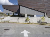 a street arrow pointing up at an outside building where the sky is clear and blue