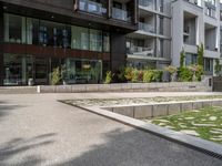 a concrete plaza near apartment buildings with many plants growing in the area behind it,