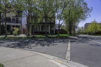 an empty street lined with parked cars and some houses in the background of this photo