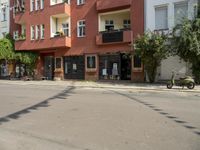 there are multiple buildings on this street near a building with bikes and a motorbike in front