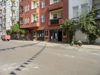 there are multiple buildings on this street near a building with bikes and a motorbike in front