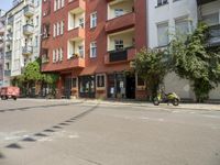 there are multiple buildings on this street near a building with bikes and a motorbike in front