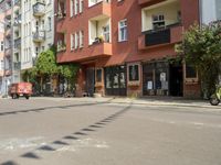 there are multiple buildings on this street near a building with bikes and a motorbike in front