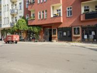 there are multiple buildings on this street near a building with bikes and a motorbike in front