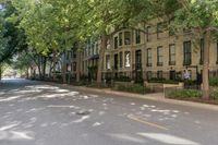 a city sidewalk lined with apartment buildings next to each other, in a row with trees