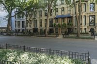 a city sidewalk lined with apartment buildings next to each other, in a row with trees