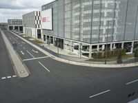 a city street with the road in front of a large building and a man standing at the bottom of the road on the sidewalk