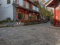 a cobbled sidewalk lined with red brick houses and green trees on both sides of it