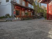 a cobbled sidewalk lined with red brick houses and green trees on both sides of it