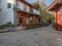 a cobbled sidewalk lined with red brick houses and green trees on both sides of it