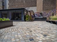 several plants sit in decorative concrete planters along the sidewalk of a building that is very modern