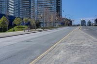 a city street with street lamps and a brick paved road near a skyscraper block under construction