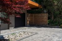 the patio has stone pavers in it and green trees behind it for privacy from the sun