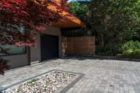 a brick patio area with rocks and gravel next to a building on the corner of a driveway