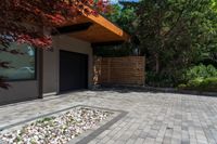 a brick patio area with rocks and gravel next to a building on the corner of a driveway