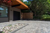 a brick patio area with rocks and gravel next to a building on the corner of a driveway