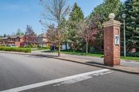 an entrance to a home along with trees and a street light on one corner, and a brick pillar with a sign reading love