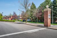 an entrance to a home along with trees and a street light on one corner, and a brick pillar with a sign reading love