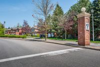 an entrance to a home along with trees and a street light on one corner, and a brick pillar with a sign reading love