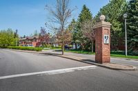 an entrance to a home along with trees and a street light on one corner, and a brick pillar with a sign reading love