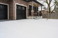 a large brown brick home in the snow with trees in front of it and the driveway covered with snow