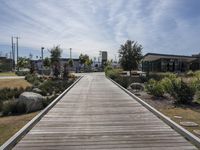 a wooden walkway in a public park near a beach with trees and plants surrounding it