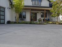 a white house and some large garage doors, along with a patio area and bushes outside