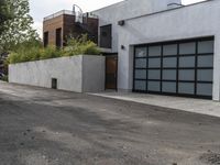 a white garage and brick wall next to an alley way with trees and shrubs surrounding the garage