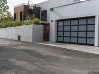 a white garage and brick wall next to an alley way with trees and shrubs surrounding the garage