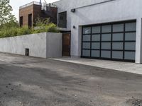 a white garage and brick wall next to an alley way with trees and shrubs surrounding the garage