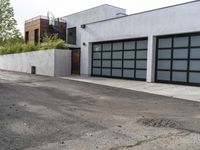 a white garage and brick wall next to an alley way with trees and shrubs surrounding the garage