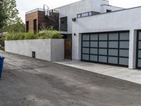 a white garage and brick wall next to an alley way with trees and shrubs surrounding the garage