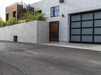 a white garage and brick wall next to an alley way with trees and shrubs surrounding the garage