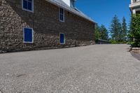 an asphalted driveway is lined with trees and stone houses as a sign for residents to keep up