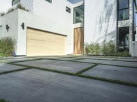 an asphalted driveway with grass in front and a wooden garage on the other side