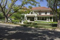 a large home sits in the middle of the street, surrounded by green trees and shrubbery