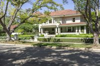 a large home sits in the middle of the street, surrounded by green trees and shrubbery