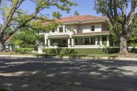 a large home sits in the middle of the street, surrounded by green trees and shrubbery