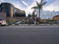 the car is parked on the side of the street with the building behind it and two trees by the side